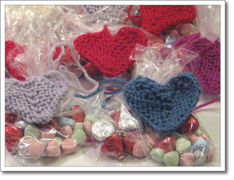 Valentine candies in baggies with knitted hearts tied around them.