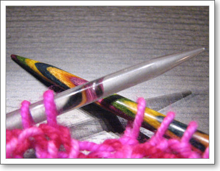 closeup of two knitting needles, one wood, one clear acrylic closeup of two knitting needles, one wood, one clear acrylic