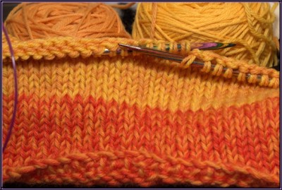 closeup of yellow and orange knitted hat in progress.