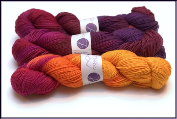 Three balls of yarn in two colorways, that go from bright yellow, to orange, to purples